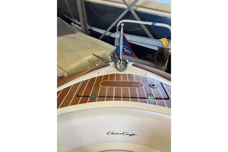 Slide: The Image of 2021 Chris-Craft Launch 27 boat with wooden deck and flag in storage. - 18