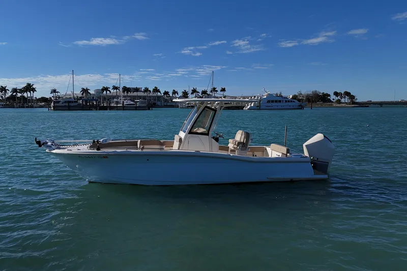 The Image of 2024 Scout 240 XSF boat on calm water with marina background. - 0