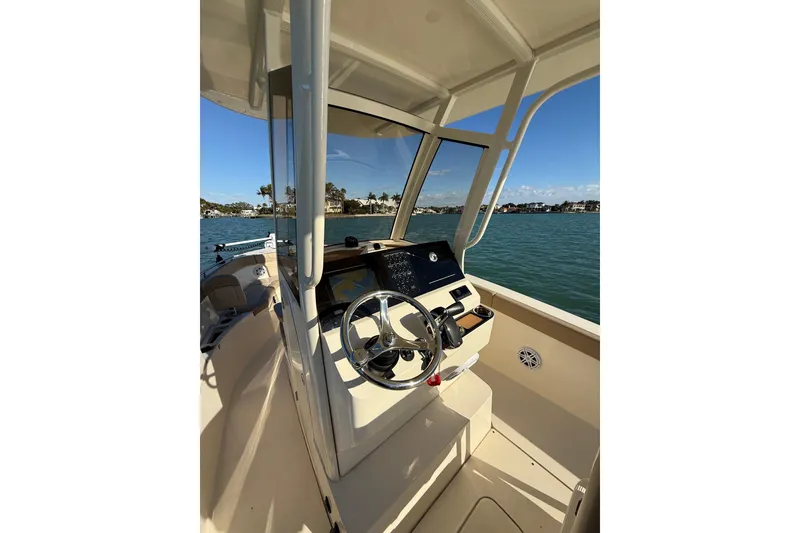 Slide: The Image of 2024 Scout 240 XSF boat interior with steering wheel, dashboard, and ocean view. - 10