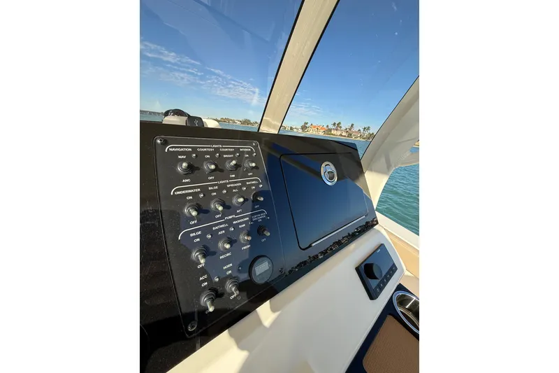 Slide: The Image of 2024 Scout 240 XSF boat dashboard with control panel and scenic water view. - 11
