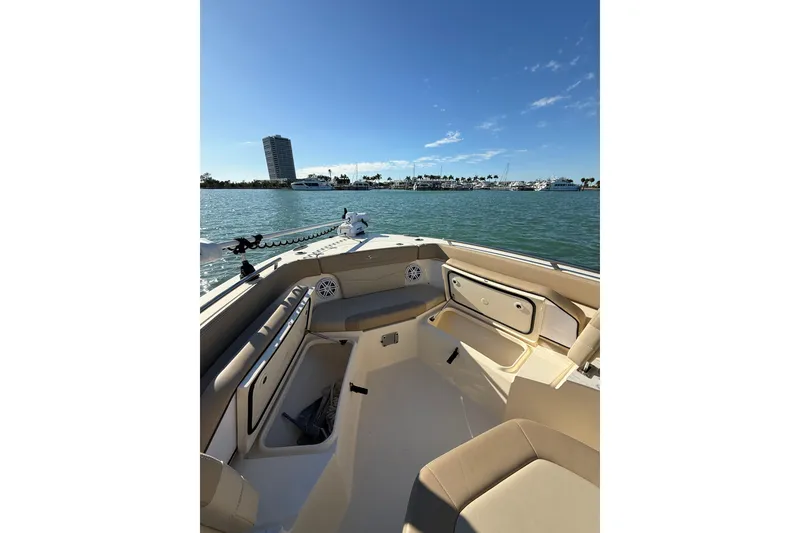 Slide: The Image of 2024 Scout 240 XSF boat interior with open storage, on calm water, clear sky. - 16