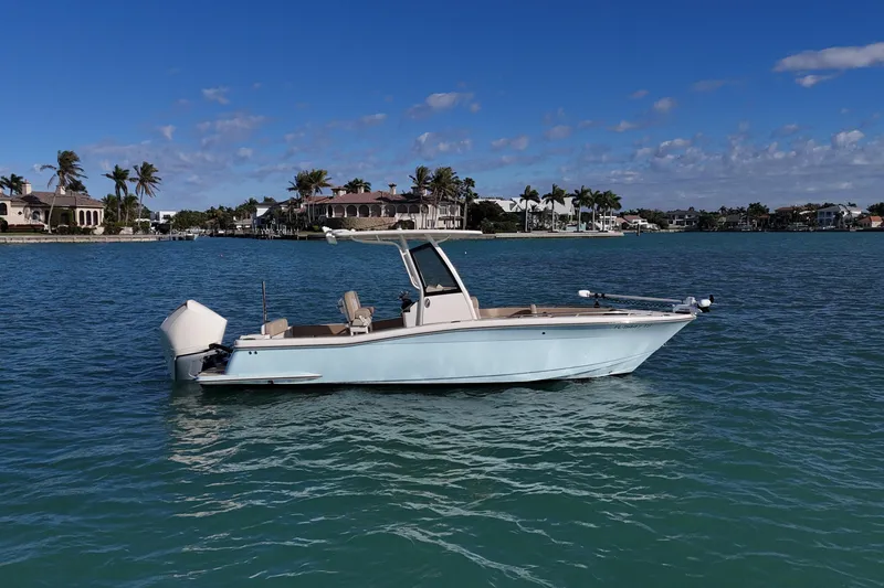 Slide: The Image of 2024 Scout 240 XSF boat on calm water with coastal homes in the background. - 3