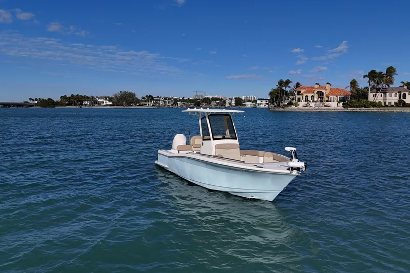 Slide: The Image of 2024 Scout 240 XSF boat on calm water with coastal homes in the background. - 4