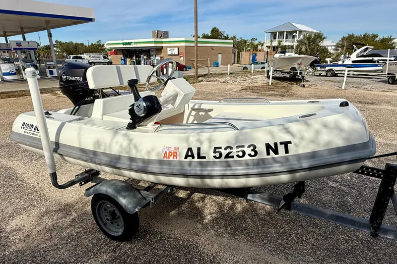 Slide: The Image of 2023 Rigid Boats 10 Sport on trailer, parked near gas station and convenience store. - 2
