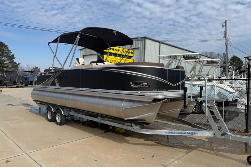 The Image of 2026 Avalon LSZ Quad Lounger Shift pontoon boat on trailer, outdoor dealership display. - 0