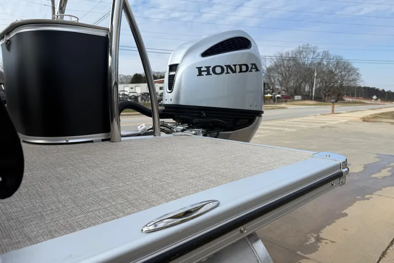 Slide: The Image of 2026 Avalon LSZ Quad Lounger Shift with Honda outboard motor, parked on pavement. - 59
