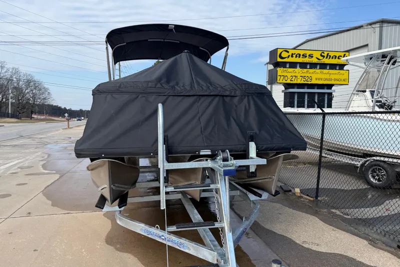 Slide: The Image of 2026 Avalon LSZ Quad Lounger Shift boat on trailer, covered, outside Grass Shack dealership. - 63