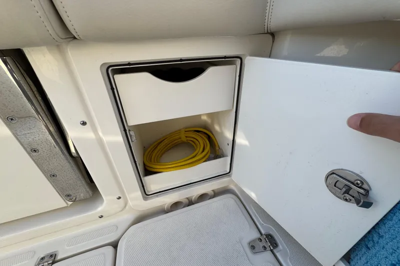Slide: The Image of Storage compartment on 2023 Boston Whaler 250 Outrage boat with yellow cable inside. - 11