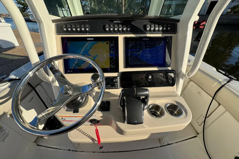 Slide: The Image of 2023 Boston Whaler 250 Outrage boat dashboard with steering wheel and navigation screens. - 14