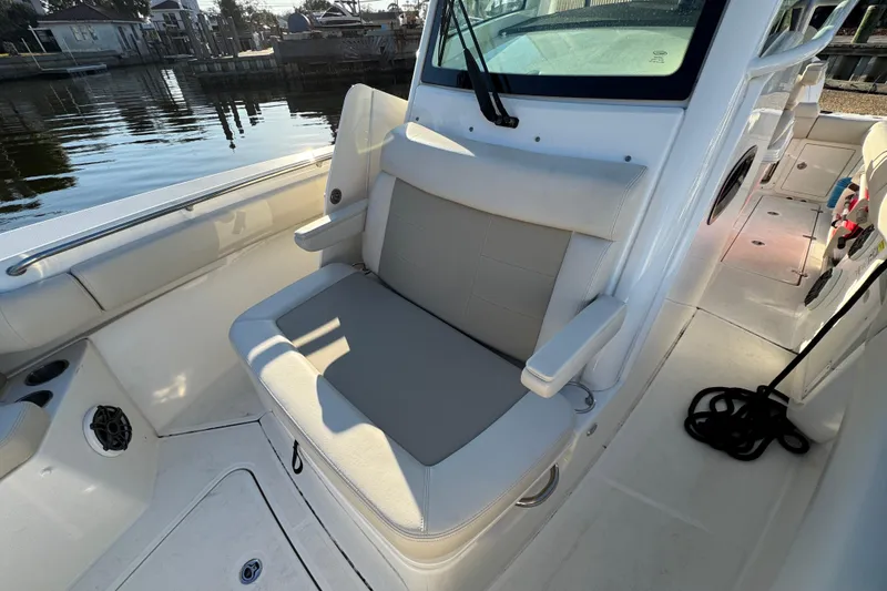 Slide: The Image of 2023 Boston Whaler 250 Outrage boat interior with cushioned seating and waterfront view. - 22