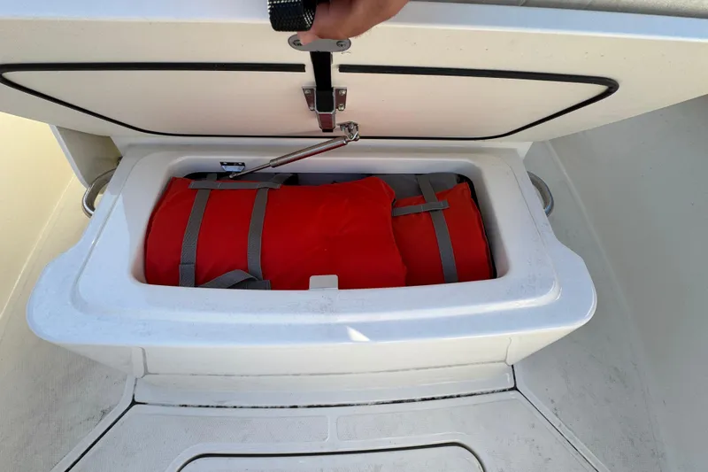 Slide: The Image of Storage compartment on 2023 Boston Whaler 250 Outrage with red life jacket inside. - 23