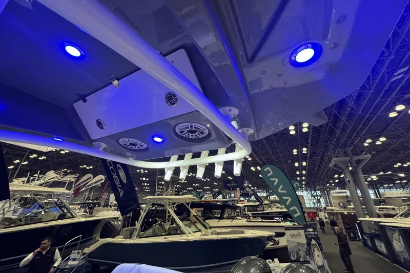 Slide: The Image of 2026 Cobia 245 Center Console boat showcased at an indoor exhibition with blue LED lights. - 11