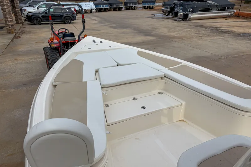 Slide: The Image of 2026 Bulls Bay 2400 boat interior with seating, parked near vehicles and trailers. - 7