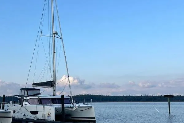 Slide: The Image of 2023 Fountaine Pajot Isla 40 catamaran docked on calm water under a clear blue sky. - 10