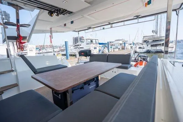 Slide: The Image of 2023 Fountaine Pajot Isla 40 catamaran interior with seating and table, docked at marina. - 51