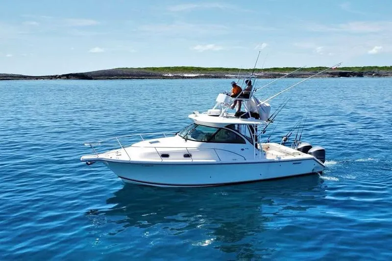 Slide: The Image of 2014 Pursuit OS 345 Offshore boat with ladder and enclosed cabin, docked under a cloudy sky. - 10