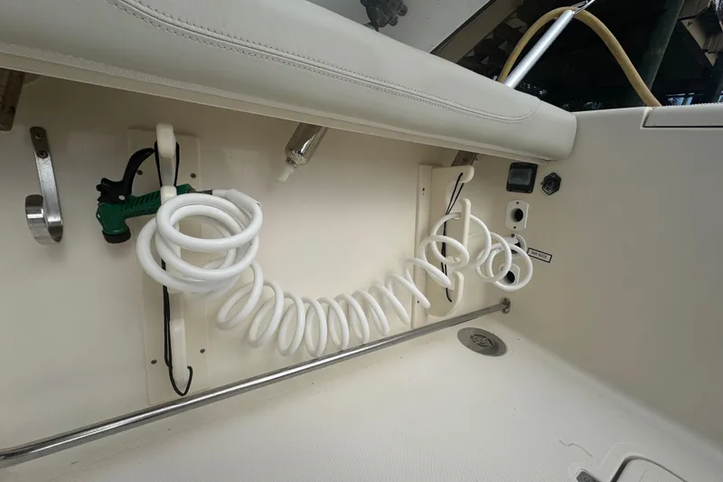 Slide: The Image of 2014 Pursuit OS 345 Offshore boat interior with coiled hose and utility features. - 27