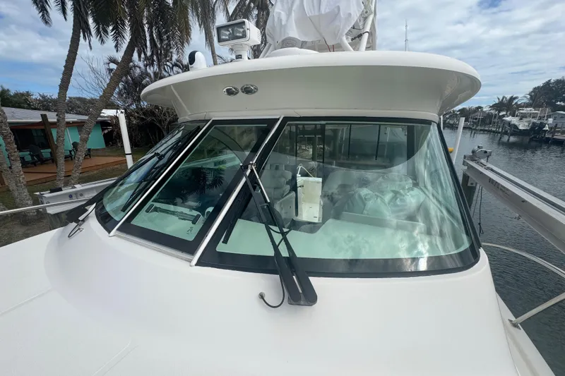 Slide: The Image of 2014 Pursuit OS 345 Offshore boat with sleek windshield and marina backdrop. - 3