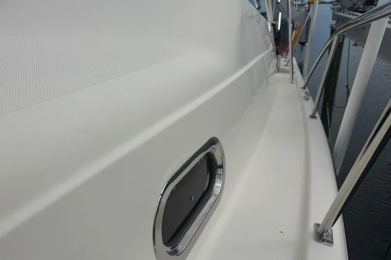 Slide: The Image of 2014 Pursuit OS 345 Offshore boat deck with stainless steel railing and porthole. - 37