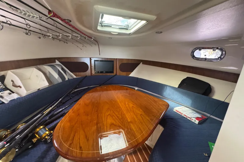 Slide: The Image of 2014 Pursuit OS 345 Offshore cabin with fishing rods, table, and seating area. - 61