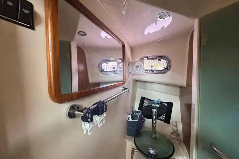 Slide: The Image of 2014 Pursuit OS 345 Offshore boat bathroom with mirror, sink, and porthole window. - 66