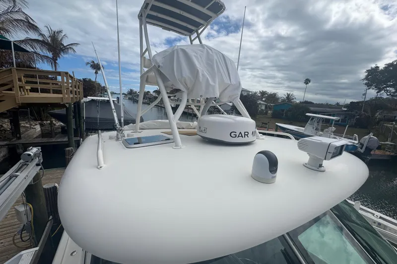 Slide: The Image of 2014 Pursuit OS 345 Offshore boat with radar and navigation equipment docked by palm trees. - 9