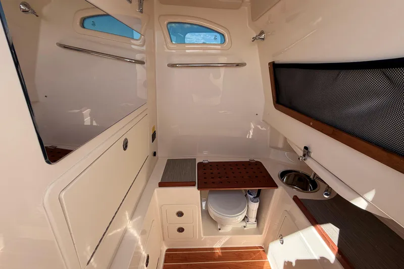 Slide: The Image of Interior of 2026 Grady-White Canyon 306 boat, featuring a compact bathroom with sink and storage. - 25