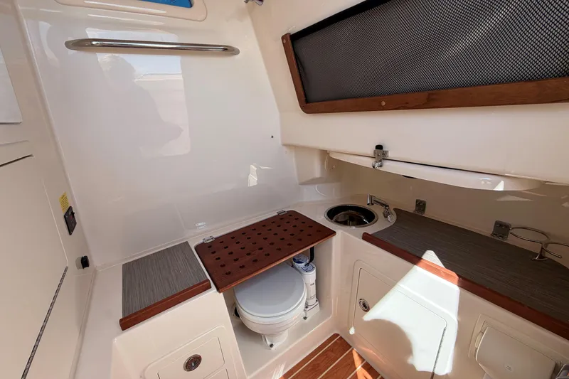 Slide: The Image of 2026 Grady-White Canyon 306 boat interior with compact bathroom and sink area. - 26