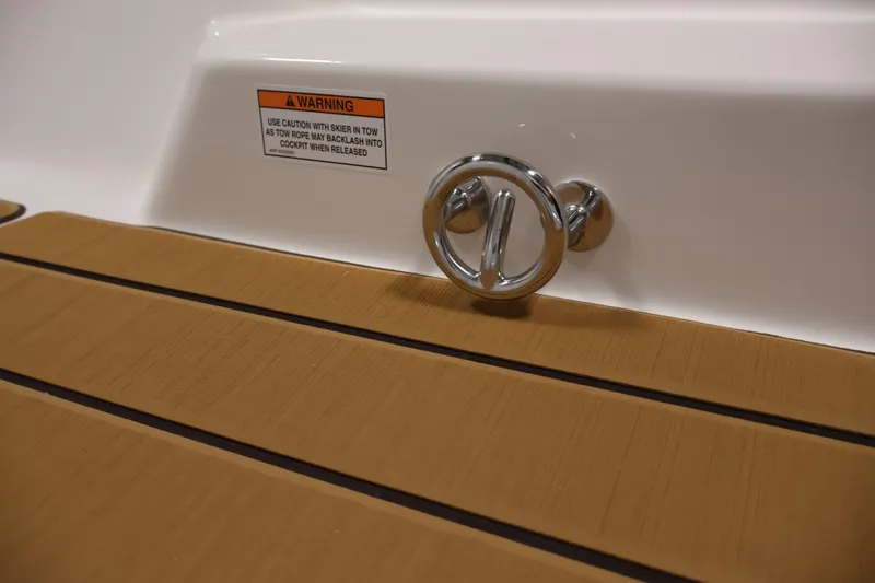 Slide: The Image of Bayliner V20i 2026 boat detail with chrome fixture and warning label on wooden deck. - 32