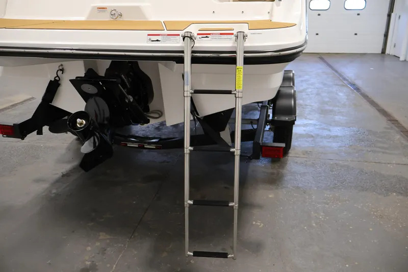 Slide: The Image of 2026 Bayliner V20i boat rear view with ladder and trailer in a garage. - 33