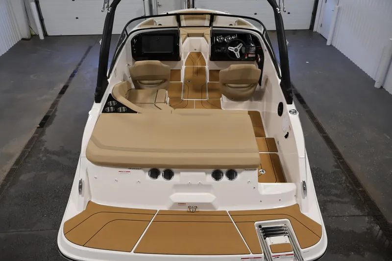 Slide: The Image of 2026 Bayliner V20i boat interior with tan seating and modern dashboard in a garage setting. - 9