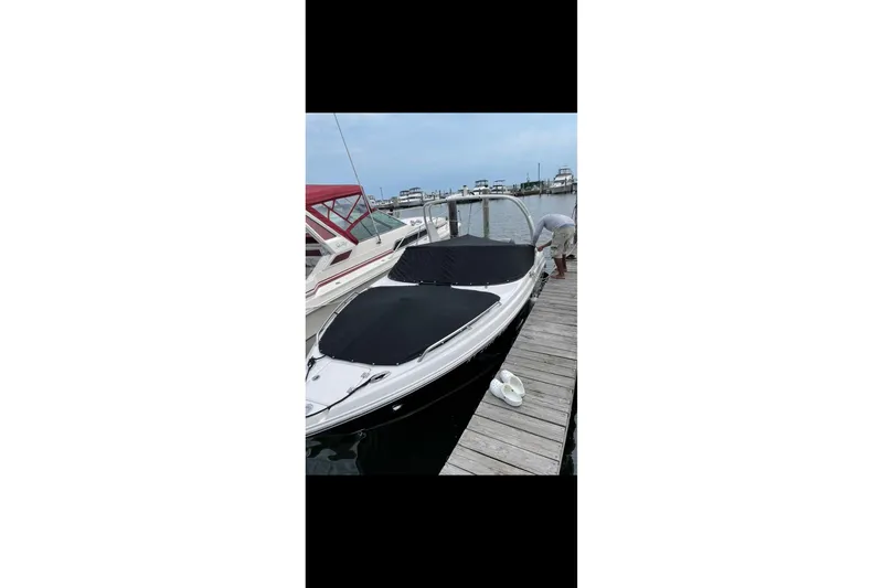 Slide: The Image of 2017 Chaparral 257 SSX boat docked with black covers, adjacent to a wooden pier. - 8