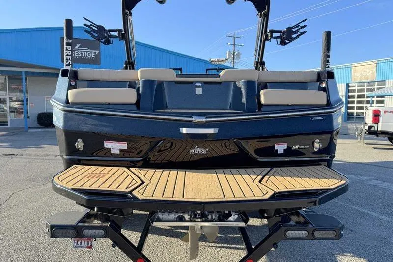 Slide: The Image of 2025 MasterCraft XT23 boat rear view at dealership, showcasing swim platform and seating. - 12