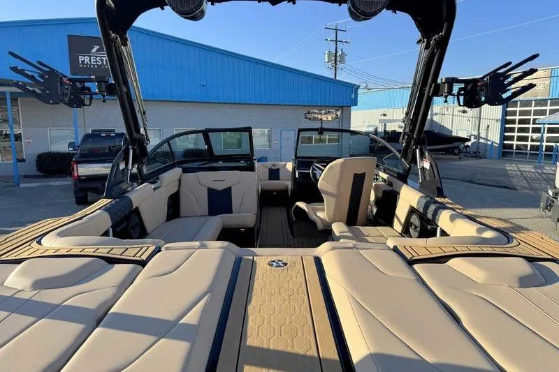 Slide: The Image of 2025 MasterCraft XT23 boat interior with beige seating and modern design at a dealership. - 13