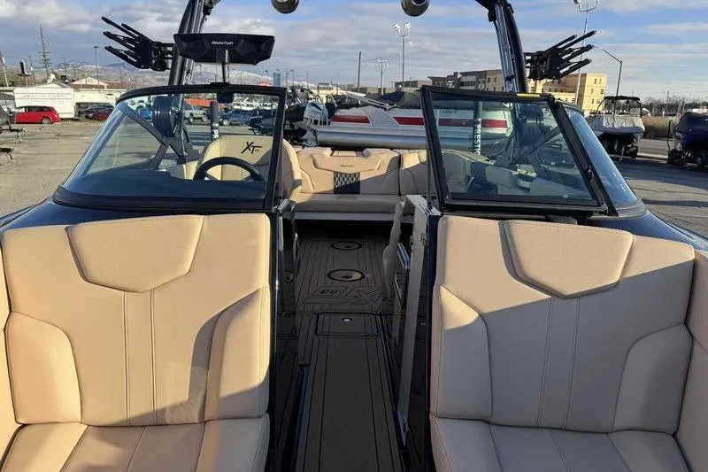 Slide: The Image of 2025 MasterCraft XT23 boat interior with beige seating and open windshield. - 9