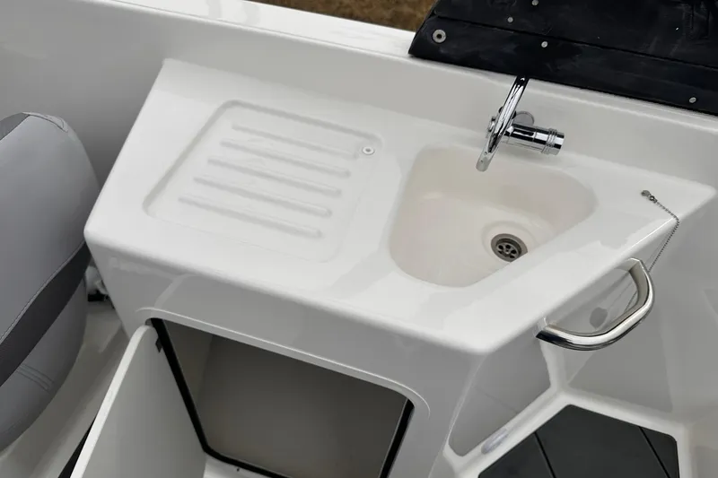 Slide: The Image of 2026 Bayliner D22 boat sink and countertop with chrome faucet and storage compartment. - 31
