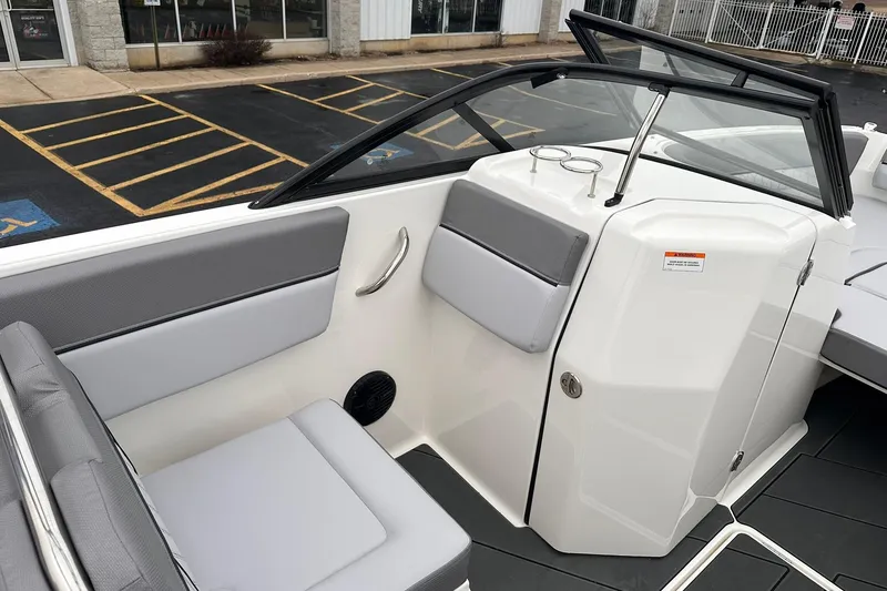 Slide: The Image of 2026 Bayliner D22 boat interior with gray seating and windshield, parked in a lot. - 37
