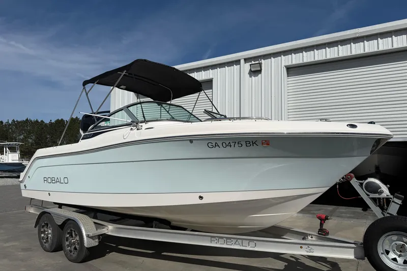 The Image of 2026 Robalo R277 Dual Console boat on trailer, parked outside a storage facility. - 0