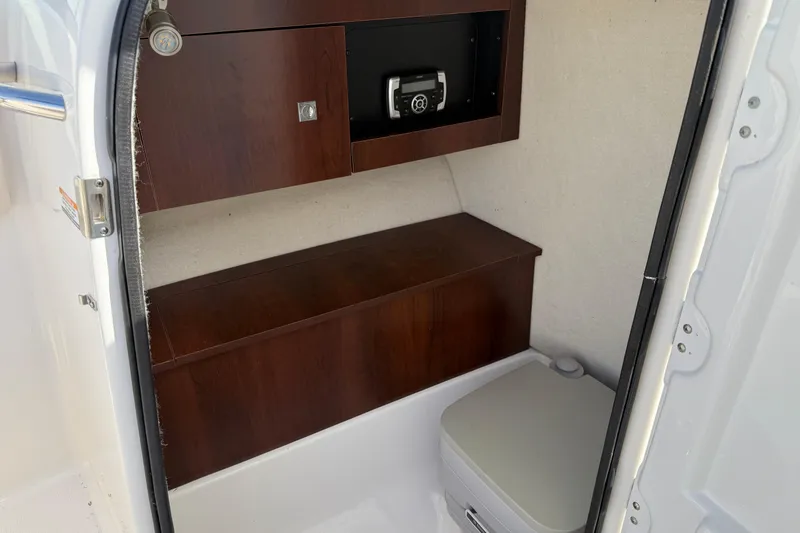 Slide: The Image of 2026 Robalo R277 Dual Console interior with wooden cabinetry and compact toilet. - 15