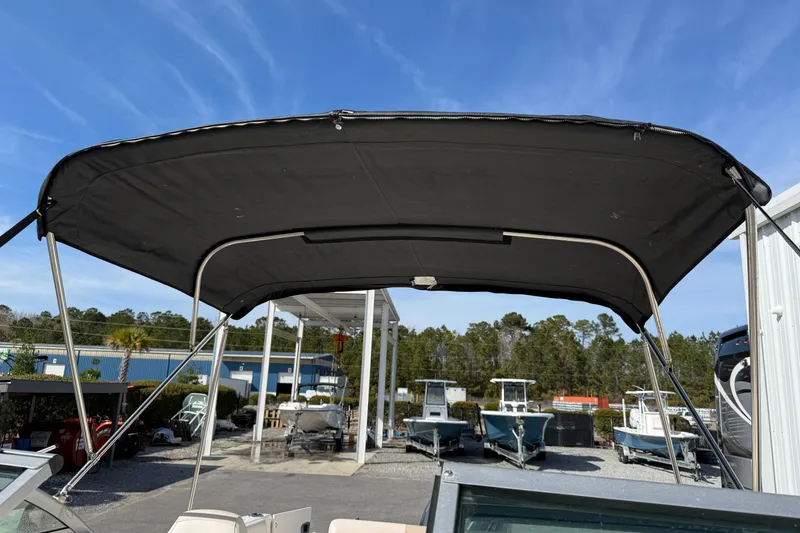 Slide: The Image of 2026 Robalo R277 Dual Console boat with black canopy, outdoor display setting. - 19