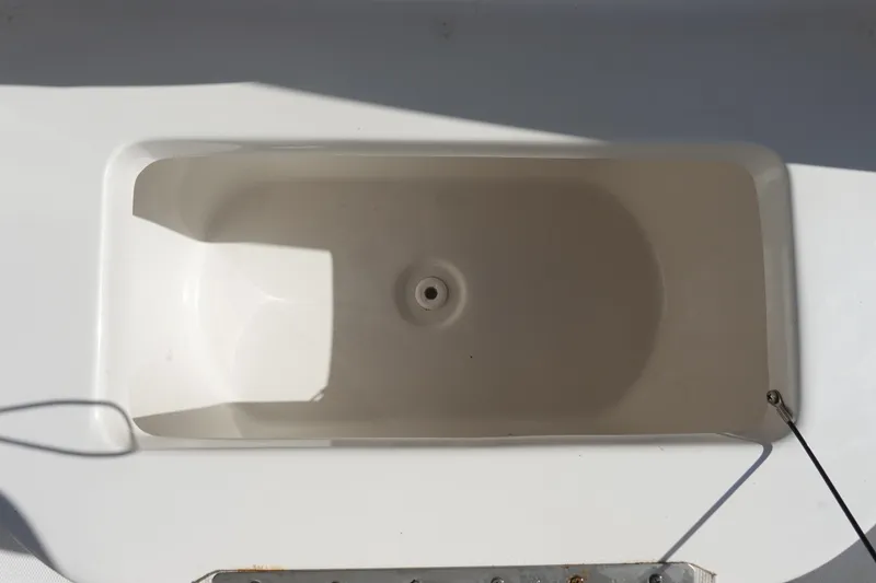 Slide: The Image of Livewell compartment on a 2022 Sea Hunt Ultra 234 boat, featuring a clean, white interior. - 26