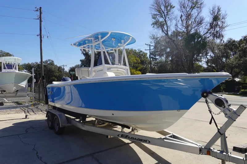 Slide: The Image of 2022 Sea Hunt Ultra 234 boat on trailer, blue and white design, parked outdoors. - 3