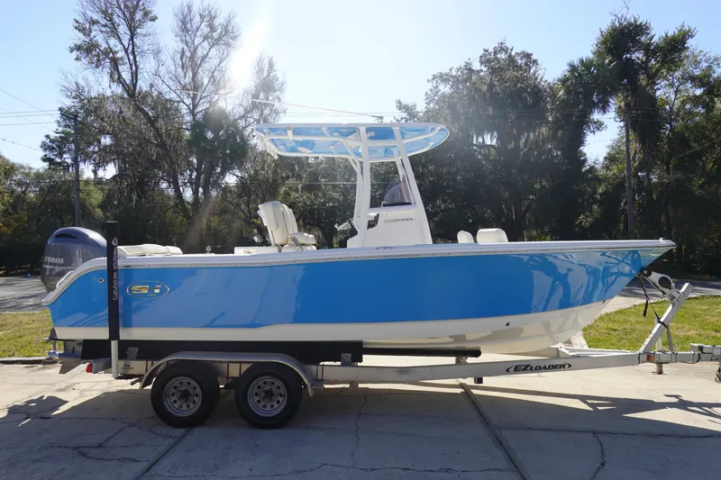 Slide: The Image of 2022 Sea Hunt Ultra 234 boat on trailer, vibrant blue hull, parked outdoors. - 4