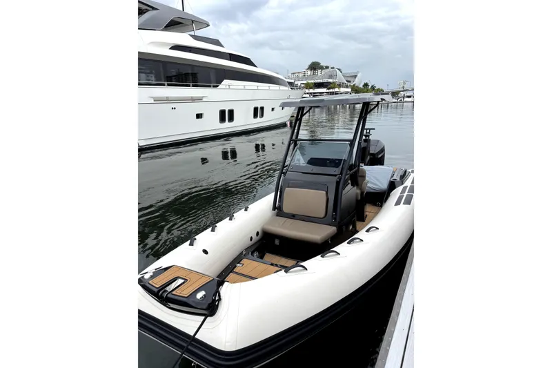 Slide: The Image of 2025 Brig NAVIGATOR22 boat docked beside a luxury yacht in a marina. - 12