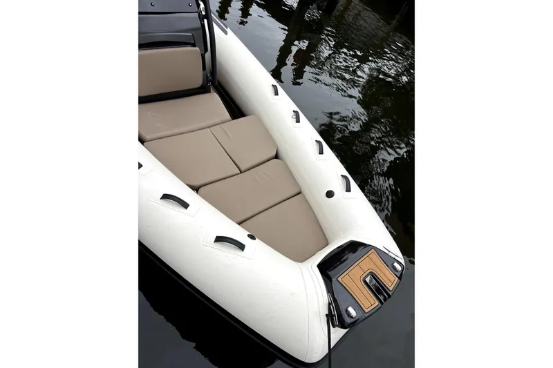 Slide: The Image of 2025 Brig NAVIGATOR22 inflatable boat with beige seating, docked on calm water. - 8