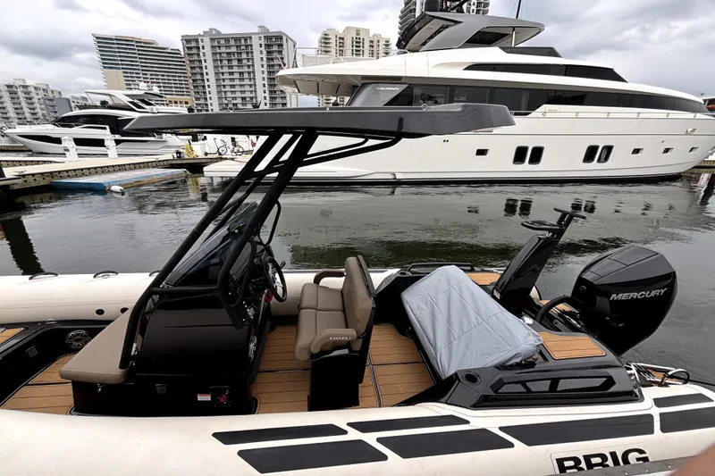 Slide: The Image of 2025 Brig NAVIGATOR22 boat docked, featuring Mercury engine, with luxury yachts in the background. - 2