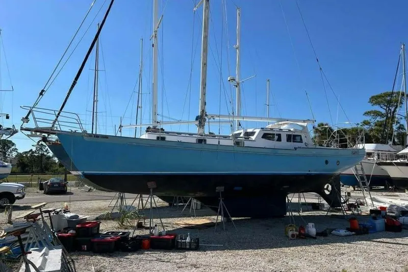 Slide: The Image of Blue Custom Baraka 46 sailboat from 1993 on dry dock, surrounded by equipment. - 3