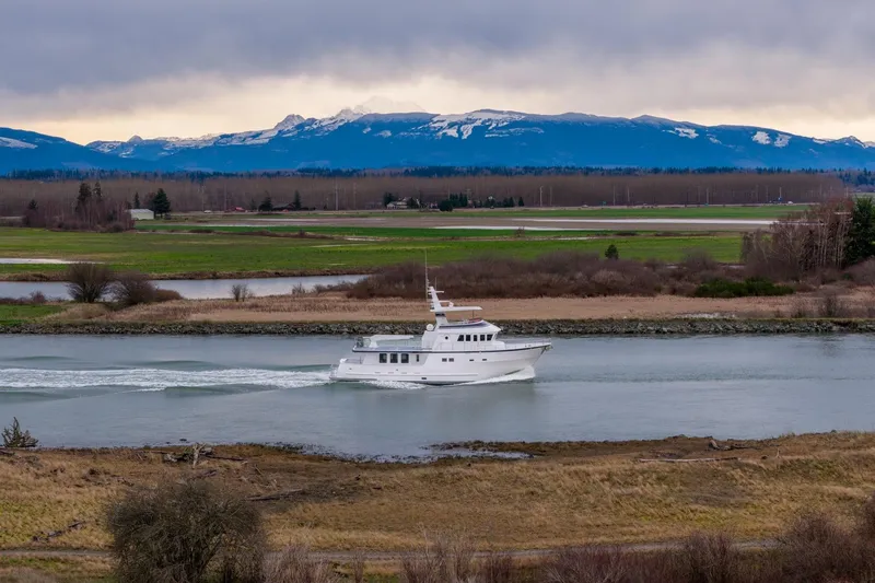 Slide: The Image of Northern Marine 80' Tri-Deck yacht cruising on a river with scenic mountain backdrop. - 3
