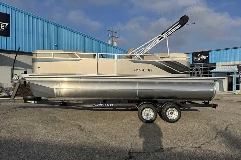 The Image of 2026 Avalon 2180 23 Venture QL pontoon boat on trailer, parked outside blue building. - 1