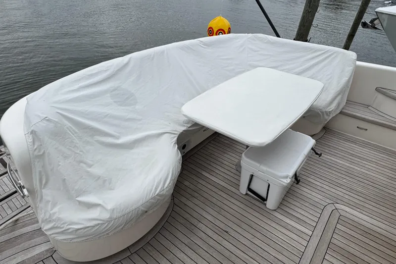Slide: The Image of 2014 Tiara Yachts 5800 Sovran deck with covered seating and table by the water. - 17